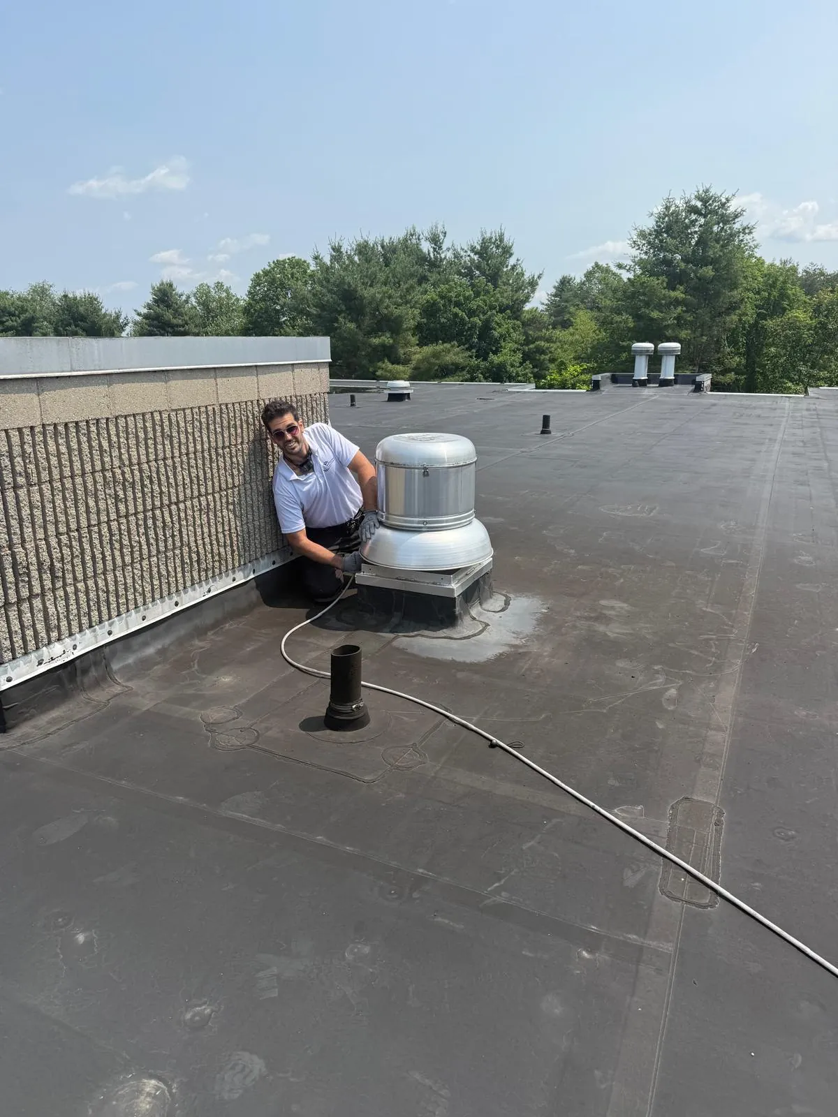 HVAC technician servicing rooftop exhaust fan unit for commercial building